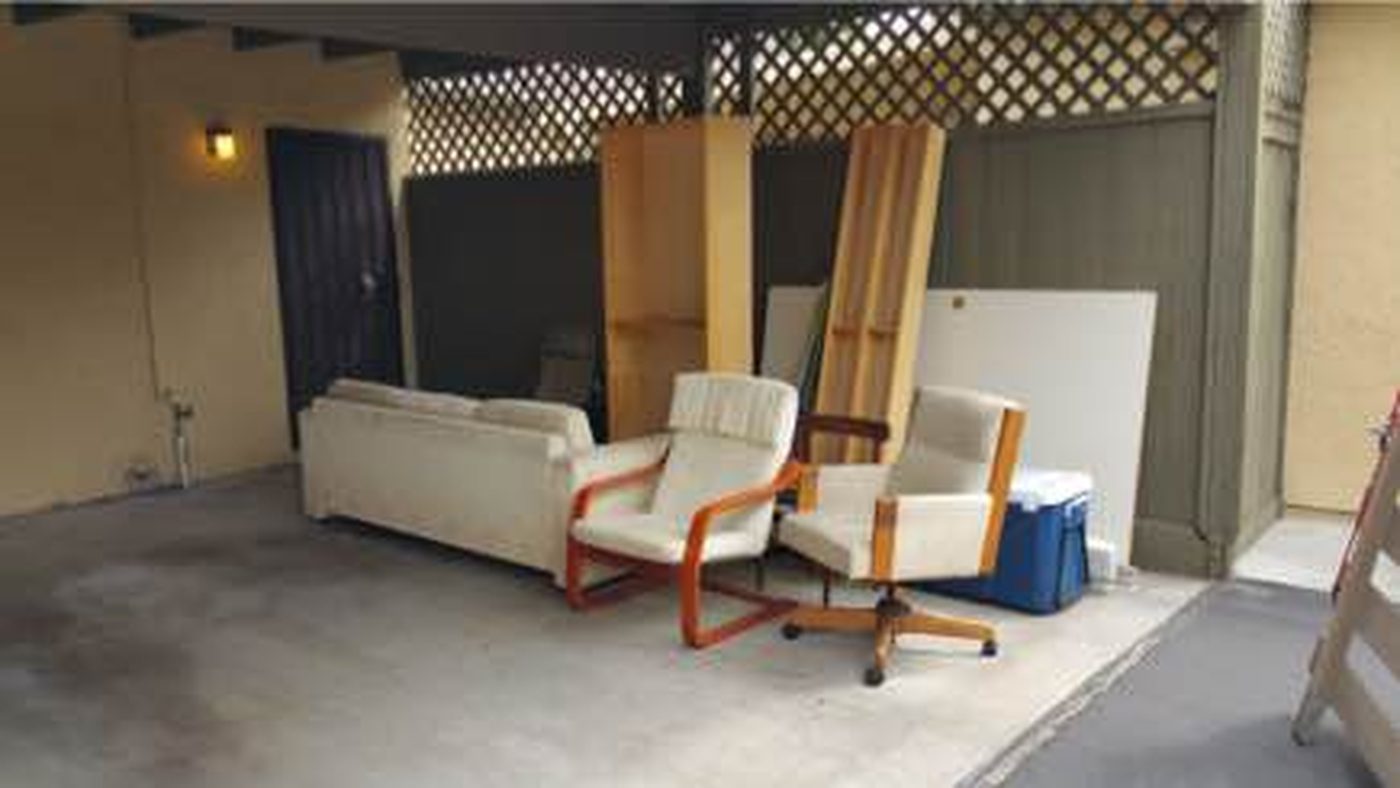 Sofa, chairs, and boards staged under a San Diego carport for pickup