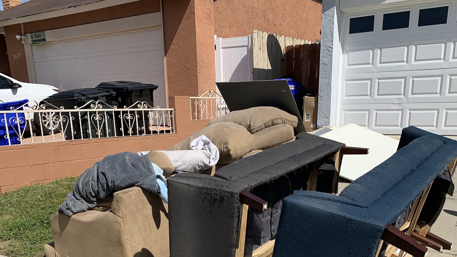 Couches and chairs staged on a San Diego driveway for pickup
